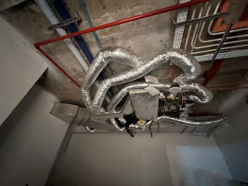 Fan coil unit with insulated flexible ducts connected above a ceiling