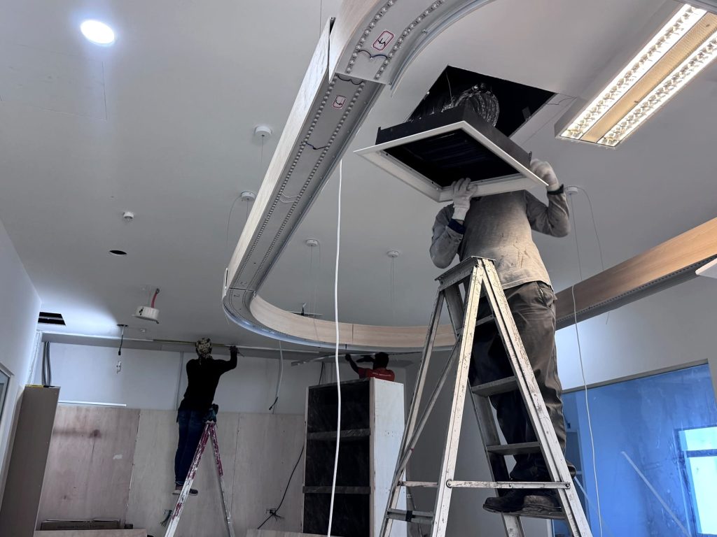 Ceiling air diffuser being lifted into position in an office ceiling