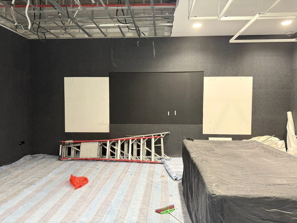 Stripped-out room with exposed ceiling grid, cables and services
