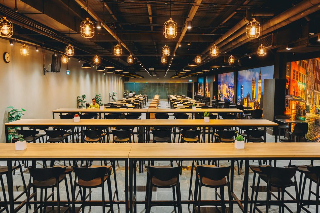 Completed staff canteen dining hall with long tables and pendant lighting